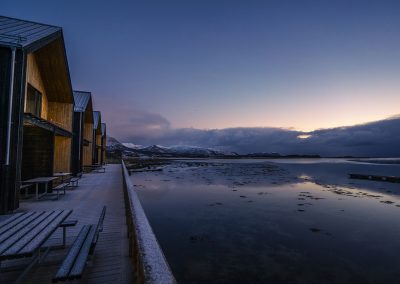 Cabins by the water at dusk with a soft blue and pink sky.