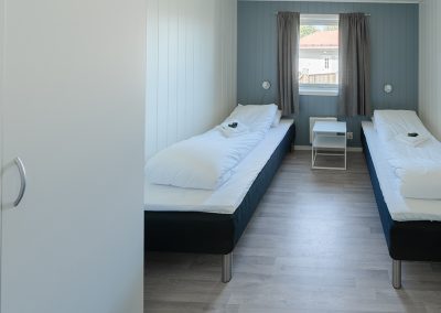 Bedroom with two single beds and a window at the far end.