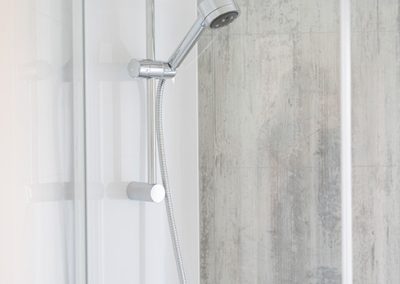 Close-up of a shower head and tiled shower wall.