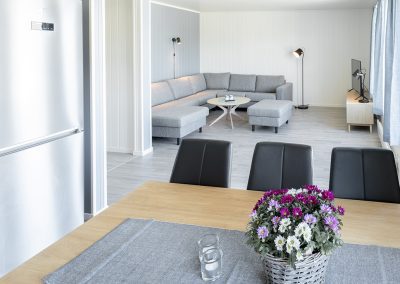 Dining table with a bouquet of flowers and a living room in the background.
