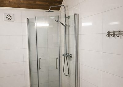 Tiled shower corner with a glass door in a bathroom.