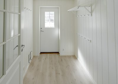 White hallway/entryway with a door and built-in wardrobes along the wall.